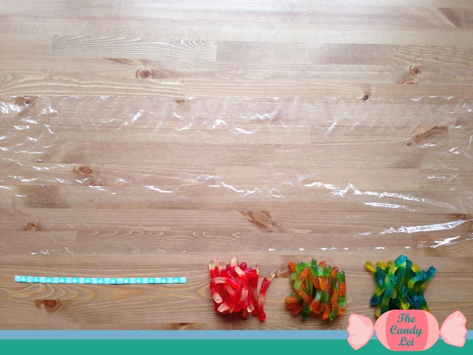 Roll out the saran wrap on a gummy worm candy lei