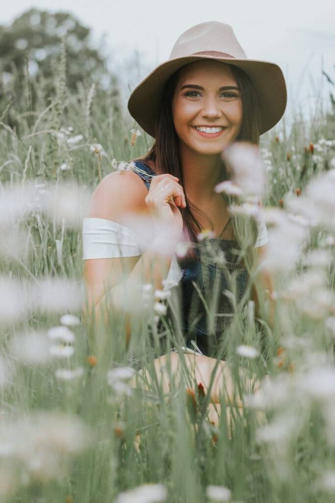 smiling in field of flowers for senior picture